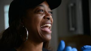 Alyssa Wilson, a Black woman in a dark baseball cap, smiles broadly.